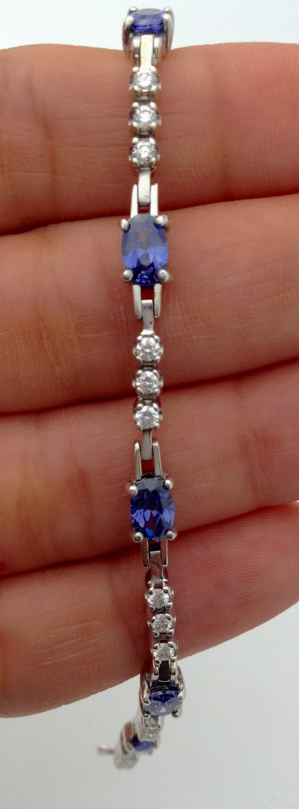 A person holding a 3.50 Ct Unheated Sapphire and 0.72 Ct Diamond Cocktail Tennis Bracelet 14k