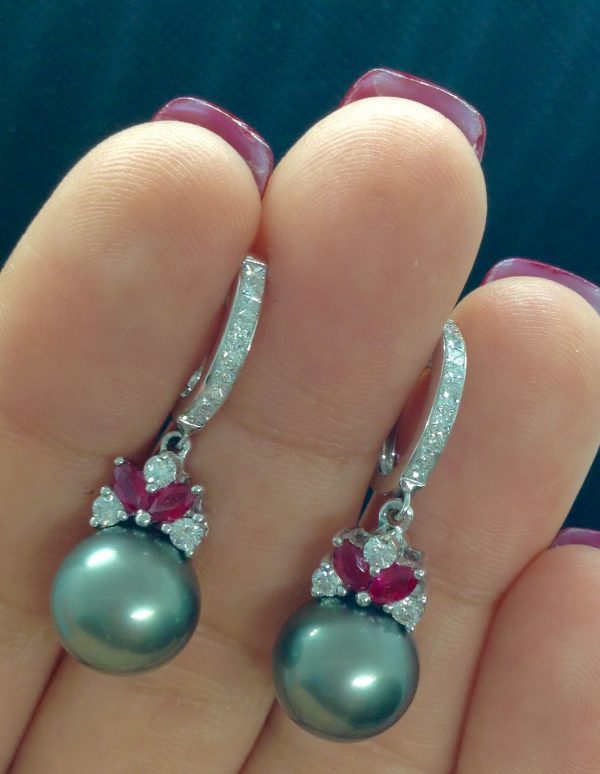 A woman holding two 18k White Gold Short Drop Tahitian 11mm Pearl with 0.85 Ct Diamonds and 0.60 Ct Ruby