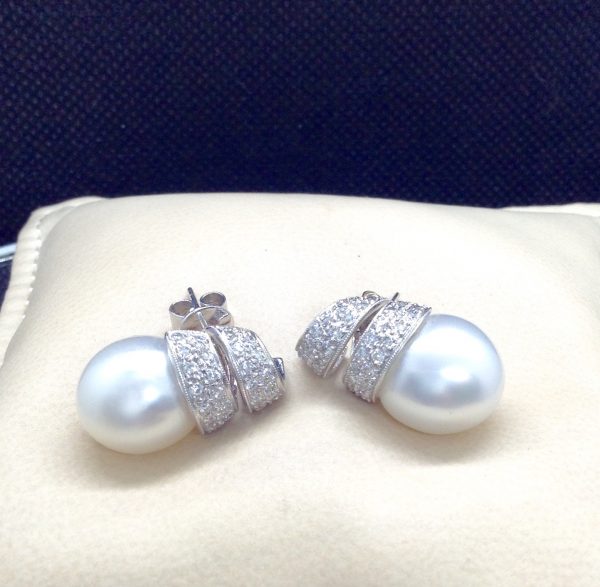14mm South Sea Pearl 18k White Gold Earring with 1.25 Ct Diamond with a Twirling Design on a pillow (front view)