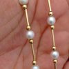 A woman holding Classy 4mm Akoya Pearls w/ 14k yellow gold beads and bars
