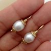 A person holding two Short Drop South Sea Cultured 10mm Pearls w/ 14k Yellow Gold Rustic Accents