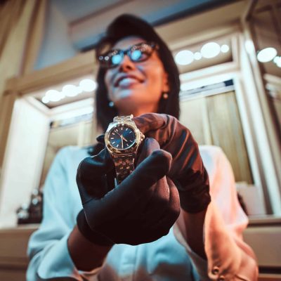 Smiling woman assistant shows exclusive watches from the new collection in a luxury jewelry store